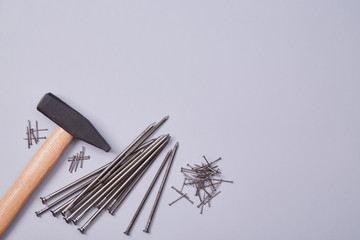 Building and renovation concept. Hammer equipment and different sizes of tacks. Isolated on wooden backdrop. Copy space