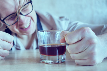 A drunk man in a shirt and tie is banging his fist on the table. Toned.