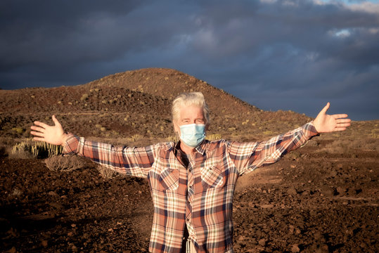 Senior man with medical face mask enjoys nature outdoors in the mountains. Partial conquest of freedom after coronavirus lockdown