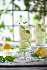 Lime, cucumber, parsley cocktail, lemonade, detox water with ice cubes in a glasses on a white plate. Detox cucumber and mint diet drink, healthy summer cooler.
