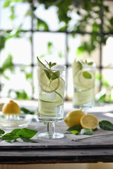 Lime, cucumber, parsley cocktail, lemonade, detox water with ice cubes in a glasses on a white plate. Detox cucumber and mint diet drink, healthy summer cooler.
