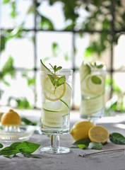 Lime, cucumber, parsley cocktail, lemonade, detox water with ice cubes in a glasses on a white plate. Detox cucumber and mint diet drink, healthy summer cooler.
