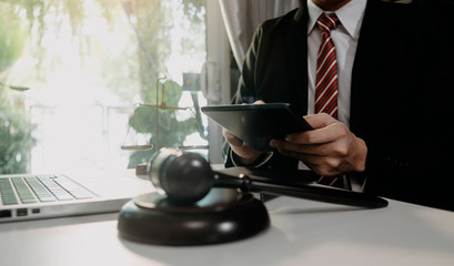 Justice and law concept.Male judge in a courtroom with the gavel, working with, computer and docking keyboard, eyeglasses, on table in morning light