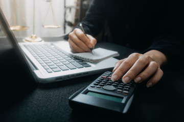 Businessman hands working with finances about cost and calculator and laptop with tablet, smartphone at office in morning light