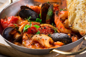 Delicious Seafood on fried pan. Tasty squid, shrimp and mussels with herbs close-up