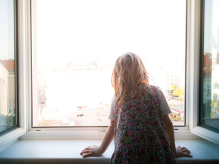 Child looks out the window alone. Lonely child. Longing for outside. Kind sieht alleine aus dem...