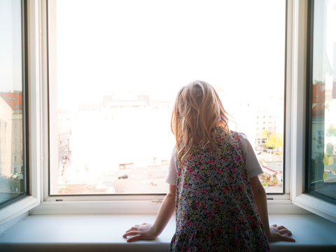 Child looks out the window alone. Lonely child. Longing for outside. Kind sieht alleine aus dem Fenster. Einsames Kind. Sehnsucht nach draussen.