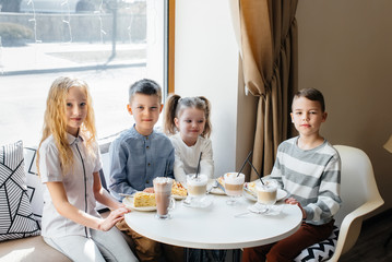 A large friendly company of children celebrate the holiday in a cafe with a delicious dessert. The day of the birth