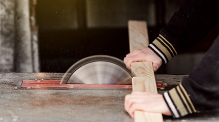 Man works on a sawmill close-up cutting a tree board. Male's work. Dangerous job. Fit the board to correct size. Manufacturing in a country house. 