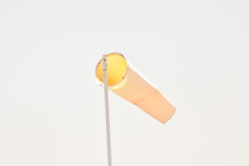 Orange wind sock against blue sky.
