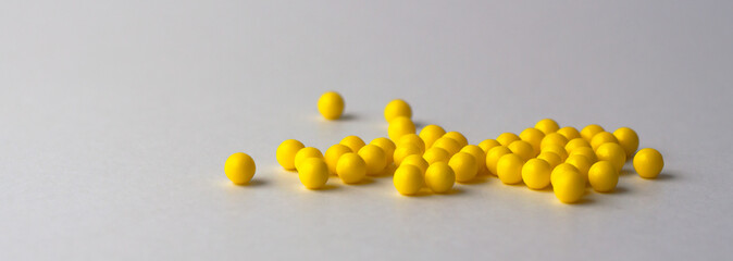 Round yellow vitamins are poured out on a white glossy table from a white plastic bottle. Concept. Place for the label. Diagnosis.