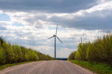 Windmills for electric power production on the background of a field road