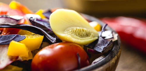 chopped vegetables in a small wooden bowl, tomatoes, mushrooms, peppers and red cabbage, small salad, vegetarian food, vibrant colors.