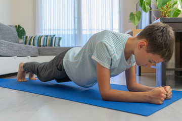 Fototapeta premium Kid doing sport exercises on mat at home. Sport, healhty lifestyle, active leisure at home