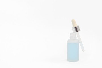 Pipette with collagen moisturizing hyaluron serum with light blue liquid in a light matt bottle with pipette isolated on grey background. 