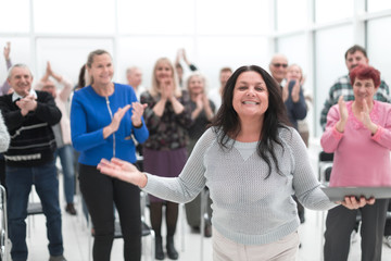 Audience at seminar applauding brunette smiling woman