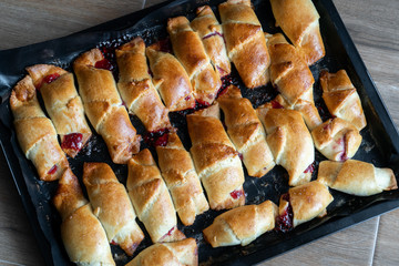 Pies with jam on a baking sheet. Cakes with jam on baking tray on wooden table. Homemade baking recipe. Tea time