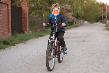 Young boy riding on bicycle with face mask due to pandemic Covid-19.
