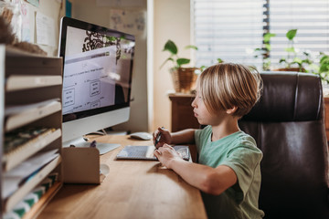 Side view of school aged boy learning from teacher conducting class