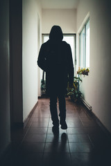 Silhouette of a man sneaking through the hallway of a house
