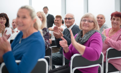 Audience of adult people listen to the speech of the lecturer applauding and smiling
