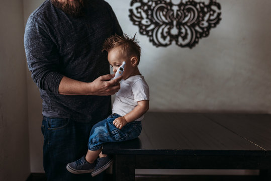 Midrange view of father taking young sons temperature at home