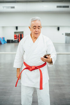 senior Karate master using mobile cell phone