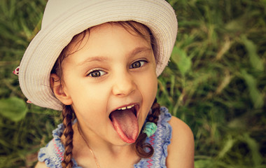 Fun kid girl looking excited her big eyes with humor face with opened mouth showing the tongue on...