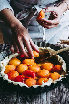 Mains d'une femme en train de pr&eacute;parer une tarte aux abricots