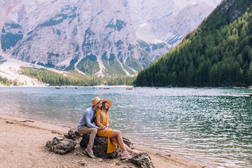 Beautiful couple sitting on stones by a wonderful lake and mount