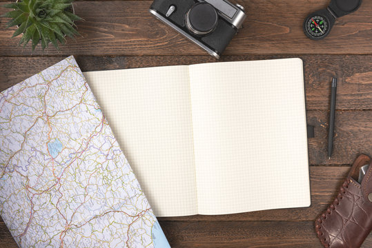 Travel planning concept. Traveler accessories. Old vintage camera with blank notepad and compass on wooden table background. Travel vacation concept. Flat lay, top view.