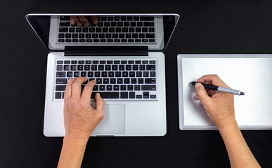 Male hands working on a laptop and graphics tablet