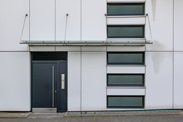 Front view on sidewalk of typical facade with swing door, canopy and windows at the entrance of...