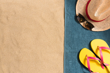 Fototapeta na wymiar Summer vacation composition. Flip flops, hat and sunglasses on sand background. Travel vacation concept. Summer background. Border composition made of towel
