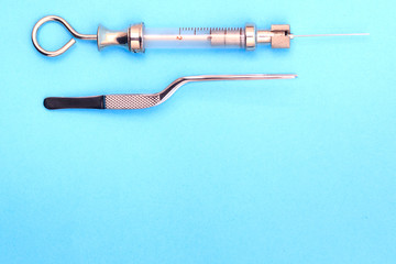 antique syringe and metal tweezers on a blue background. copyspace