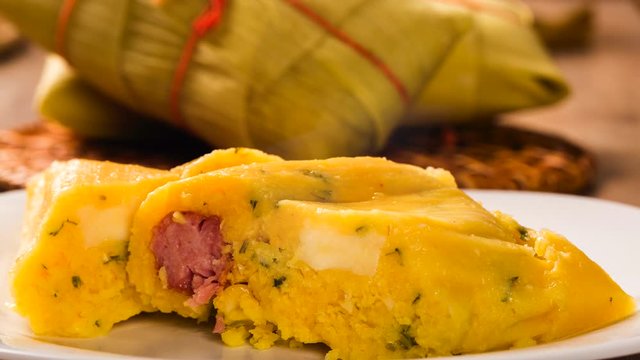 Slide shot Salty Pamonha with sausage and cheese - typical food of green corn - tasty and cheap - typical and popular street food with smoke.