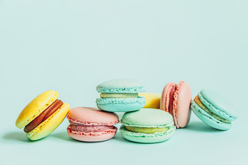 Sweet almond colorful pink blue yellow green macaron or macaroon dessert cake isolated on trendy blue pastel background. French sweet cookie. Minimal food bakery concept. Flat lay top view, copy space