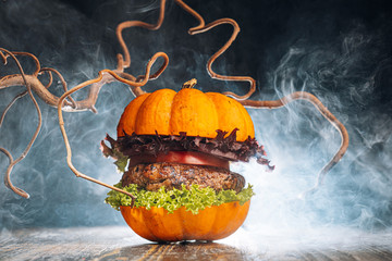 Burger Halloween. halloween concept of a burger with big beef patties with pumpkin head rolls for...