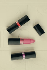 Obraz premium Three female lipsticks of red, purple and pink colors. Women's cosmetics for makeup.