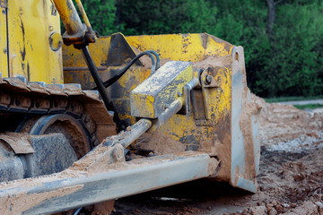Fototapeta na wymiar bulldozer stands on the sand near the forest. close-up on the metal bucket of a bulldozer. laying a new road along the forest