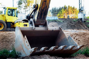 bulldozer stands on the sand near the forest. close-up on the metal bucket of a bulldozer. laying a new road along the forest