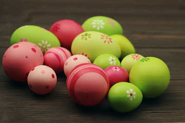 Decorated and painted pink and green easter eggs on wooden background  