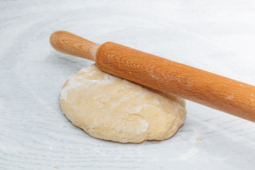 Fototapeta na wymiar dough and rolling pin on the white kitchen table. the concept of home cooking. cooking homemade dough. close up