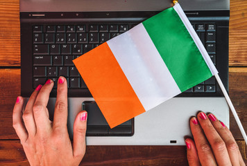 woman hands and  flag of Ireland on computer, laptop keyboard
