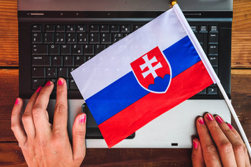 woman hands and  flag of Slovakia on computer, laptop keyboard

