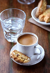 Cup of coffee with cantuccini (Italian cookies) on rustic wooden background.