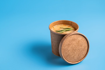 Pea soup in paper disposable cups for take-out or delivery of food on blue background.