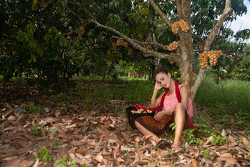 The senior Asian woman pose is sitting relaxation under longkong tree in the garden with happiness.