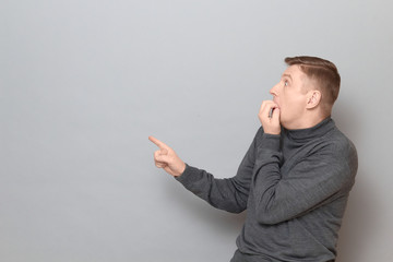 Shot of shocked frightened man pointing with finger at something awful