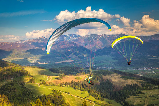 Flying paragliders from the Stranik hill over the mountainous landscape of the Zilina basin in the north of Slovakia..Mala Fatra National Park in the background, Slovakia, Europe.